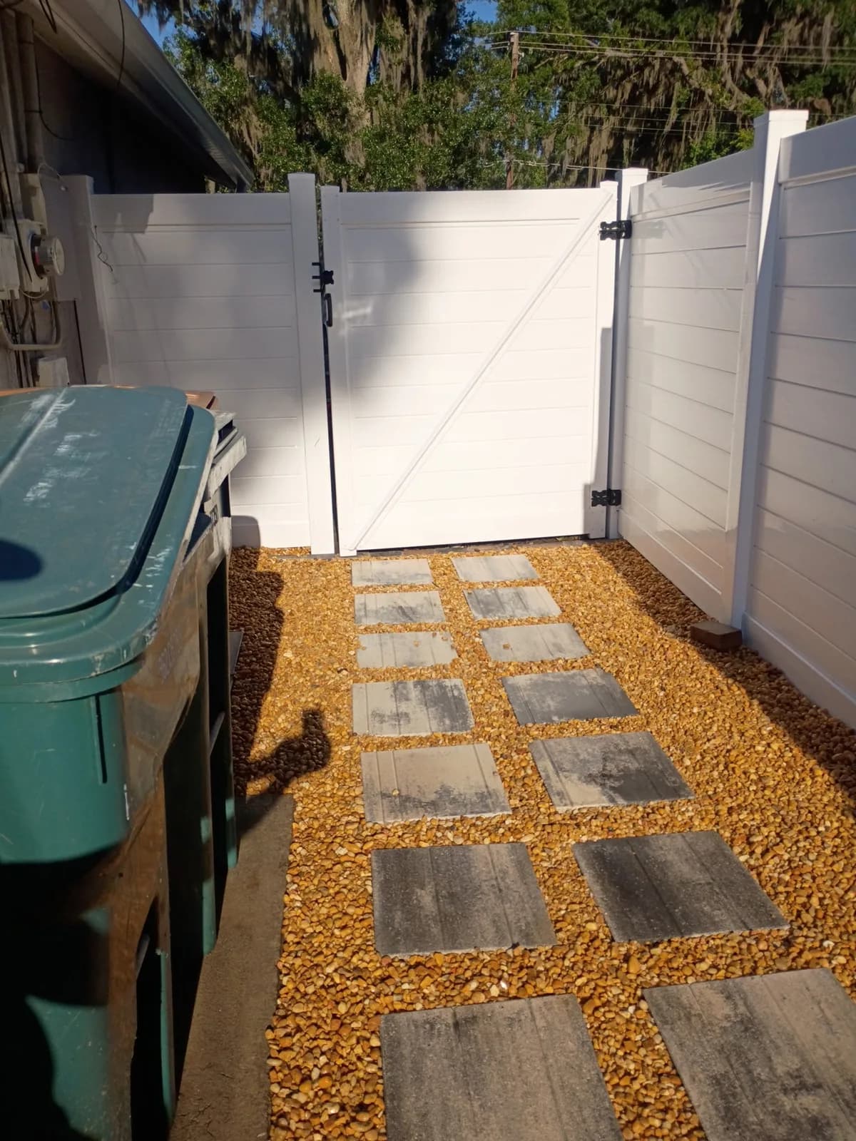 Side yard paver path set in pea gravel with new vinyl fence gate